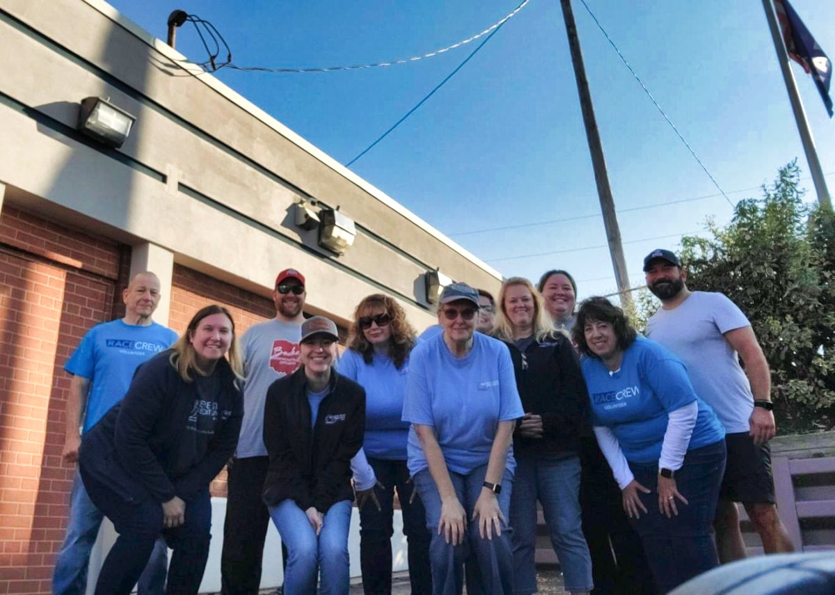 join-our-team Group of ten people, some in "CREW" shirts, standing outside building on sunny day.